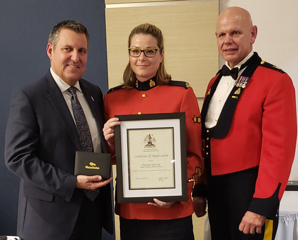 Justice Minister Cliff Cullen presents award to RCMP Const. Julie Cote as  RCMP Assistant Commissioner Scott Kolody looks on. (RCMP)